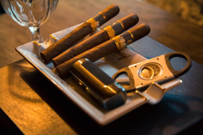 Cigars arranged on a tray with a clipper and lighter